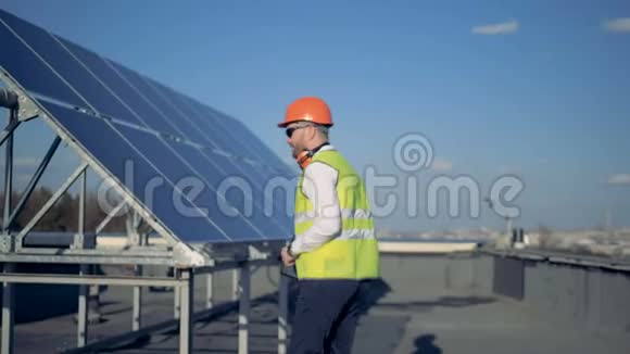 屋顶上有一块太阳能电池板还有一名工程师在上面举着他的安全帽视频的预览图