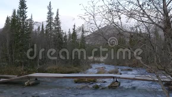 一个男子旅行者穿过一条山溪越过一座桥美丽的景色视频的预览图