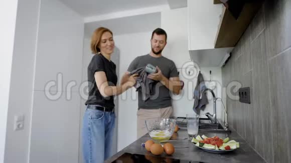 快乐的配偶们周末早上在厨房做早餐女人做煎蛋卷男人洗餐具视频的预览图