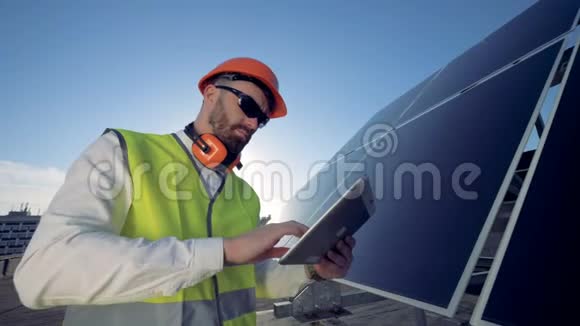 男工程师正站在屋顶上靠近一个装有平板电脑的太阳能电池视频的预览图