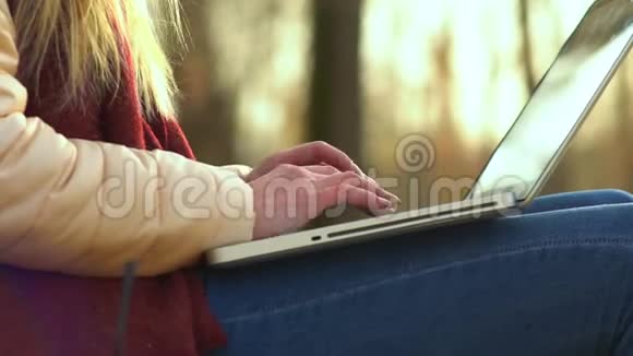女孩手在街上的笔记本电脑键盘上打字在秋天视频的预览图