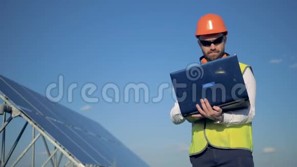 男工程师站在太阳能电池附近在他的笔记本电脑上打字替代能源概念视频的预览图