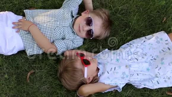 两个戴墨镜的小朋友趴在草地上头对头视频的预览图