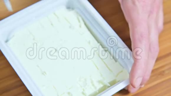 女性手的特写用一包白色的feta奶酪切一把刀做成希腊色拉的立方体视频的预览图