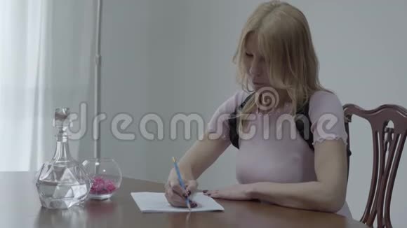 一位身材苗条金发碧眼身穿矫形胸衣的漂亮女人坐在桌子上写着一封信视频的预览图