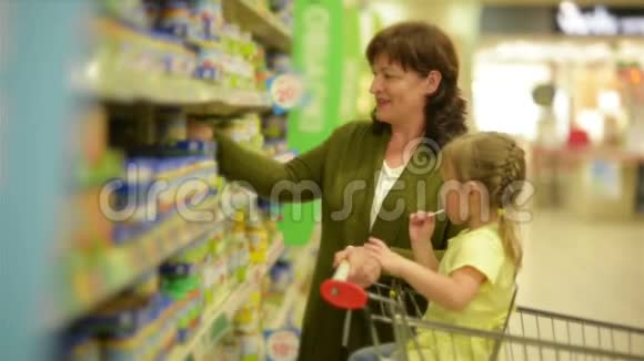 祖母和孙女正在购物中心购买物品孙女坐在购物手推车里视频的预览图