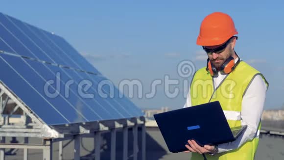 太阳能电池和一名男性施工人员在附近使用他的笔记本电脑生态动力保护理念视频的预览图