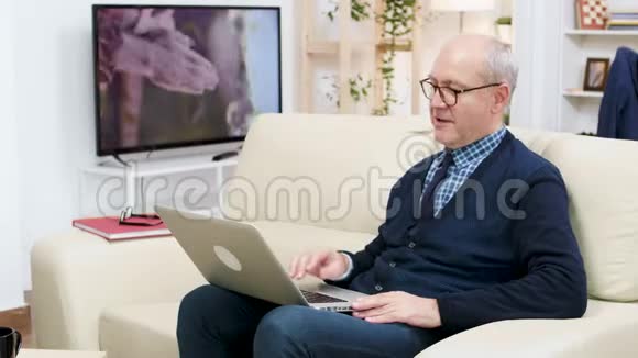 在视频通话中一对幸福的老夫妇坐在沙发上视频的预览图