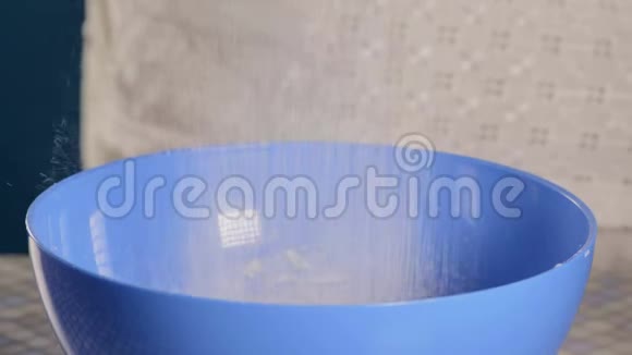 特写镜头厨师用蓝色碗里的筛子把面粉筛下来视频的预览图