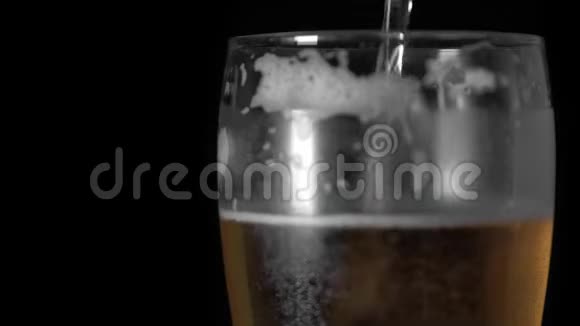 冷光啤酒倒入一个玻璃与水滴始终哑光黑色背景边框设计手工啤酒凑近了视频的预览图
