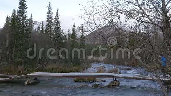 一个男子旅行者穿过一条山溪越过一座桥美丽的景色视频的预览图