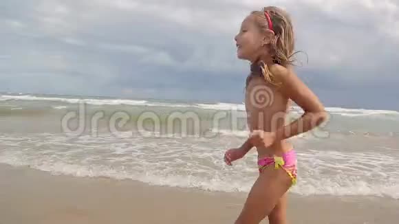一个快乐的小女孩正在享受大海浪来岸边欢度小儿女视频的预览图