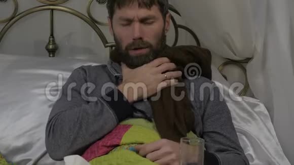 一个病人躺在床上脖子上围着一条温暖的围巾咳嗽着喝着一片药丸4K视频的预览图