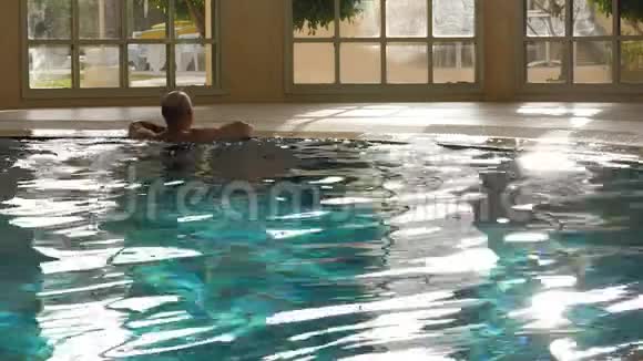 帅哥在蓝水里游泳在豪华的室内游泳池里休息视频的预览图