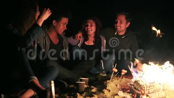 从侧面可以看到不同的人群在深夜坐在炉火旁互相拥抱做饭视频的预览图