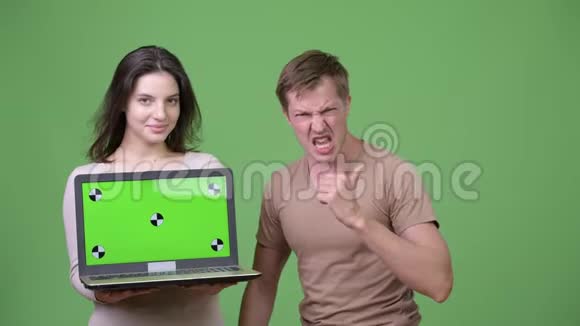 年轻的幸福夫妇一起展示笔记本电脑和好消息视频的预览图