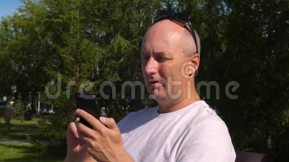 在城市公园里一个英俊的男人打着手机看着镜头视频的预览图