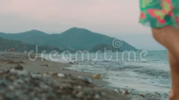 日落时在海边散步的小女孩穿裙子的女孩在海边散步视频的预览图