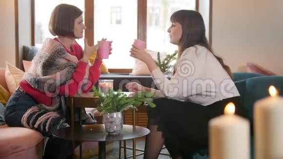 两个年轻的女人坐在咖啡馆里一边喝咖啡一边讨论一些事情视频的预览图