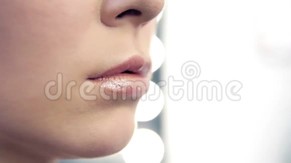 一位专业化妆师将口红涂在模特在美容院工作的嘴唇上的特写镜头近景视频的预览图