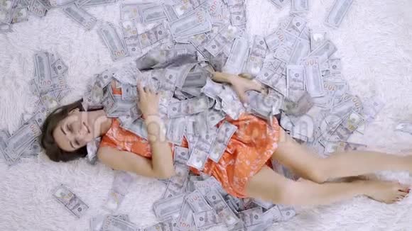 一个女孩躺在一张白色的床上一大堆钞票在空中缓慢地飞舞巨大的财富视频的预览图