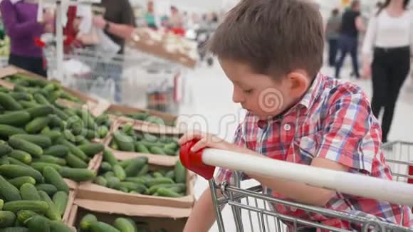 可爱的小男孩在超市里选择新鲜黄瓜视频的预览图