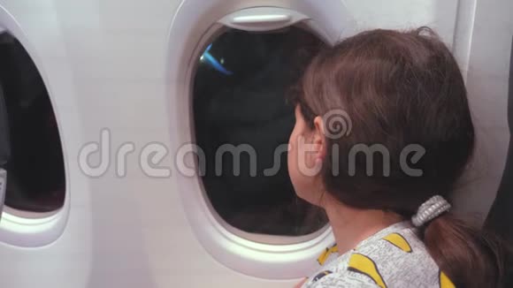 航空飞机概念年轻的少女在飞行时看着飞机在夜间的窗口飞行年轻乘客视频的预览图