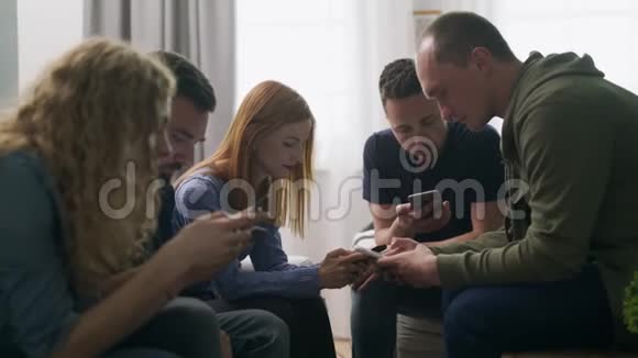 一群朋友在客厅里使用智能手机视频的预览图