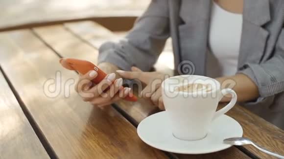 年轻女孩深色卷发坐在咖啡馆里在户外使用电话视频的预览图