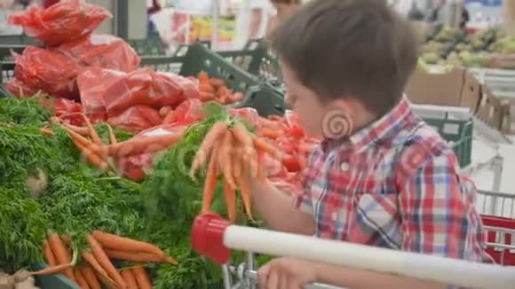 可爱的小男孩在超市里选择新鲜的有机胡萝卜有孩子的年轻家庭的健康生活方式视频的预览图