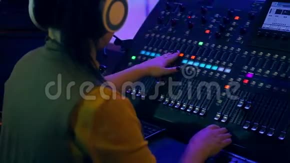 女士DJ耳机后混合控制台工作在彩色照明从后面拍摄视频的预览图