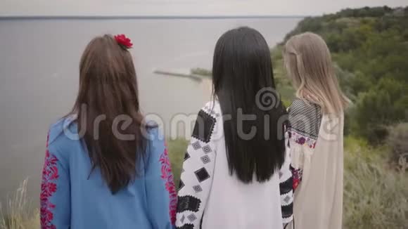 三个可爱的女朋友穿着夏天的长时装在湖边或湖边散步视频的预览图