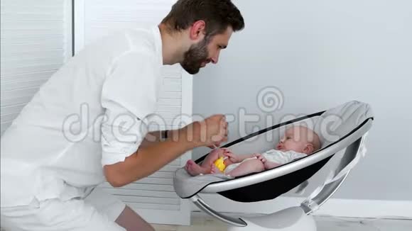 父亲和躺在现代婴儿床上的婴儿玩耍现代风格的概念视频的预览图