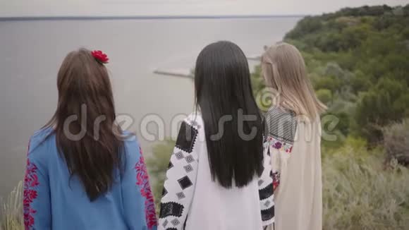 三个可爱的女朋友穿着夏天的长时装在湖边或河边散步视频的预览图