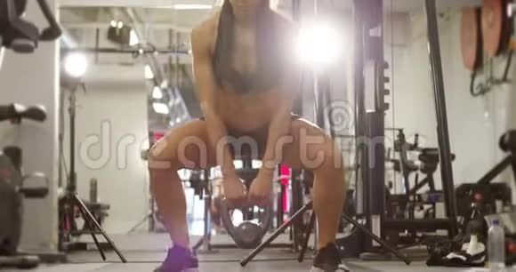 强大的健康女性锻炼在健身房做水壶铃蹲视频的预览图