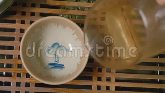 茶大师把热茶从玻璃壶中倒入茶碗从头顶看视频的预览图