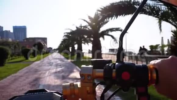 在度假小镇上POV骑着一辆电动自行车在一条红色的自行车道上骑着棕榈树视频的预览图