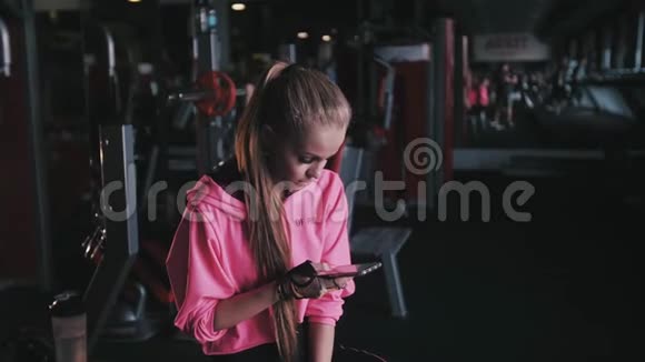 活跃的女孩使用智能手机在健身健身房视频的预览图