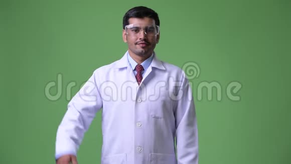 年轻英俊的波斯男子医生戴着防护眼镜指着视频的预览图