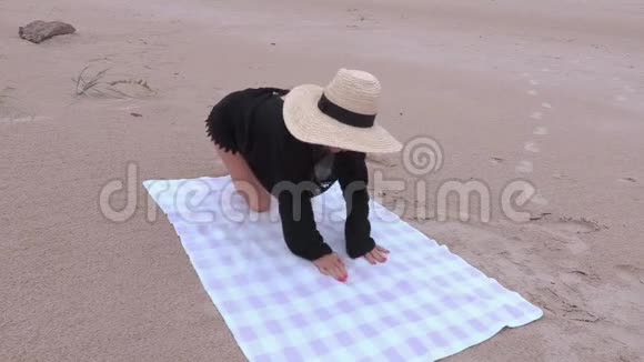女人坐在沙滩毛巾上视频的预览图