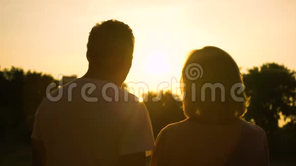 年长夫妇拥抱一起看日落浪漫约会视频的预览图