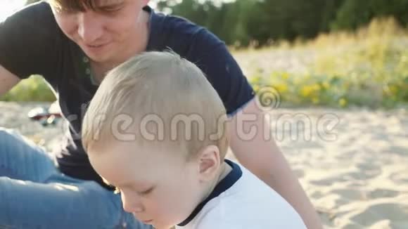 一位年轻的父亲和一个小儿子在海滩上玩孩子们玩具视频的预览图