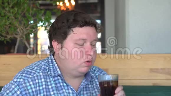 在咖啡馆或餐馆喝可乐的胖子视频的预览图