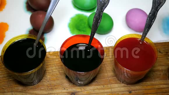 女人用不同的颜色画复活节彩蛋用彩色染料蘸杯子视频的预览图