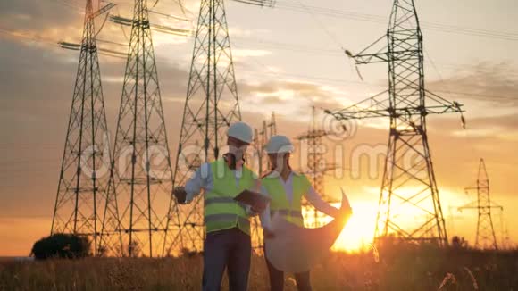 电力线路工人在日落背景下与施工计划一起工作视频的预览图