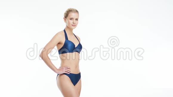 年轻美丽健康和自然的金发女人穿蓝色泳衣摆在孤立的白色背景体育健身视频的预览图