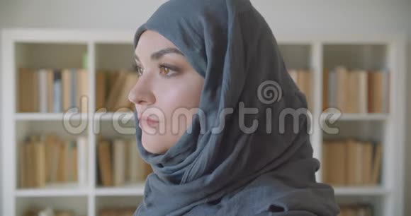 年轻的穆斯林有魅力的女商人的特写照片看着镜头在室内图书馆里开心地微笑着视频的预览图