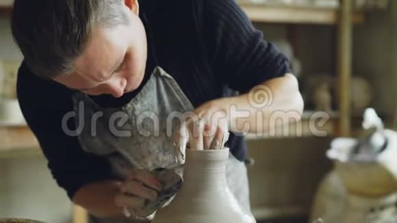 小陶工在陶工车间工作时用粘土在抛石轮上制作陶瓷花瓶的特写镜头视频的预览图