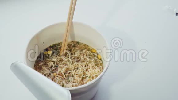 有人把方便面和热水和筷子混合在纸碗里视频的预览图