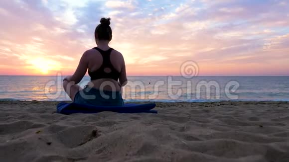 日出时在海滩上练习瑜伽的女人看风景全景视频的预览图
